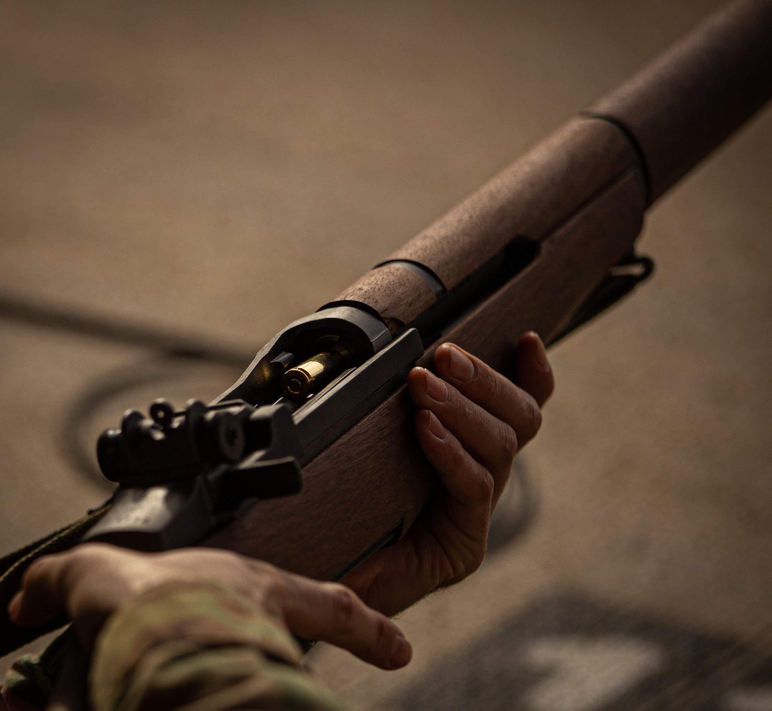 A close-up of a person's hand holding a gun with a round of ammunition inside.