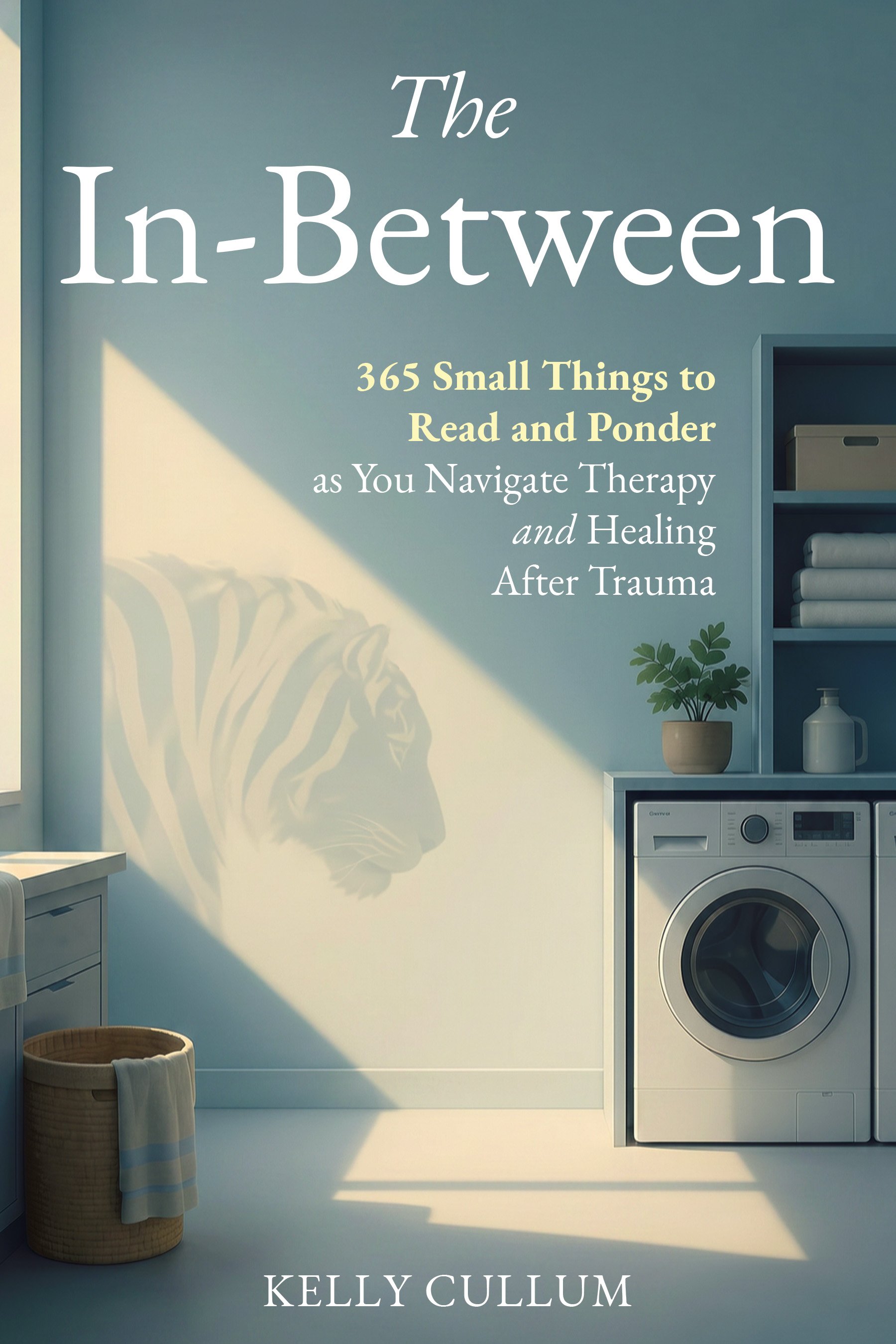 Book cover titled 'The In-Between: 365 Small Things to Read and Ponder as You Navigate Therapy and Healing After Trauma' by Kelly Cullum. The background shows a laundry room with a washing machine, shelves with towels, and a potted plant. Light creates a shadow of a tiger on the wall.