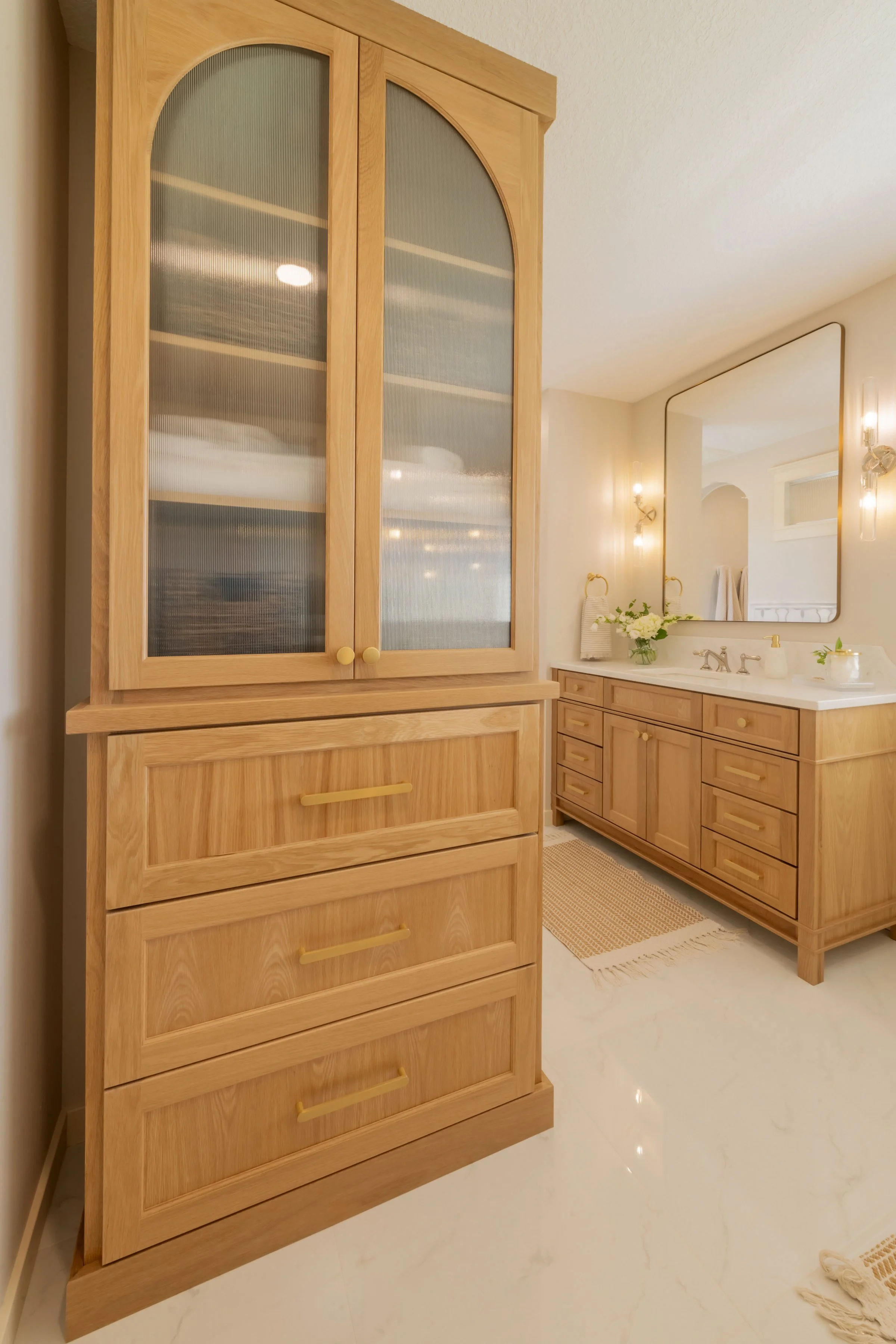 Bathroom with wooden cabinets, a large mirror, and soft lighting.