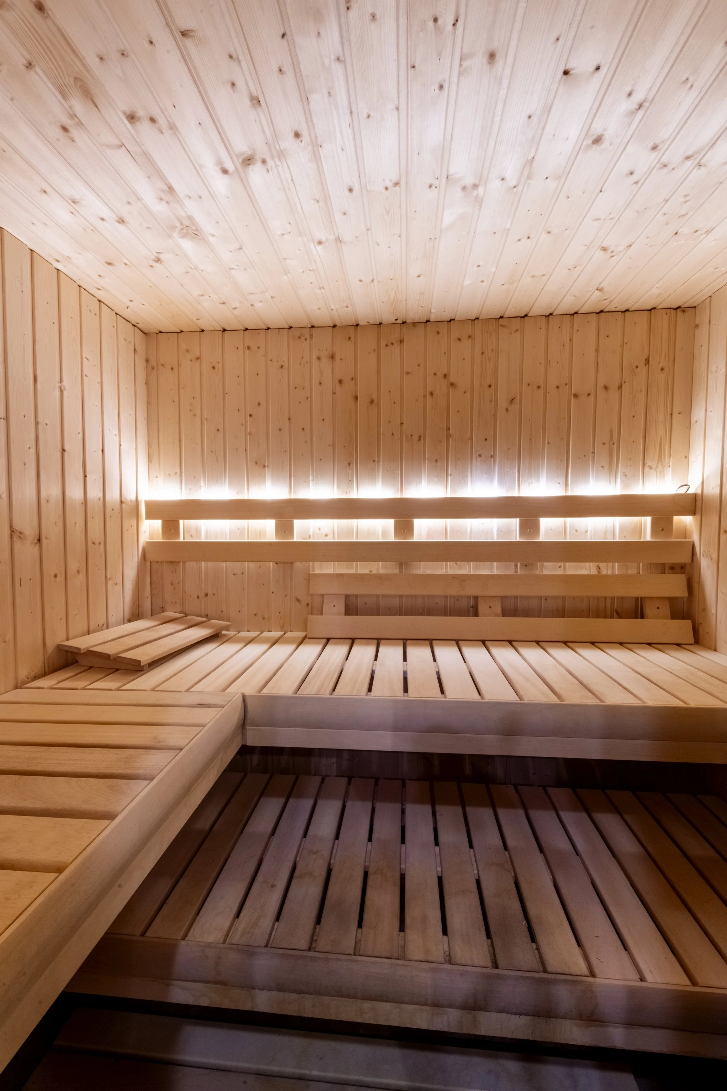 Inside a wooden sauna with wooden benches and walls, illuminated by soft lighting.