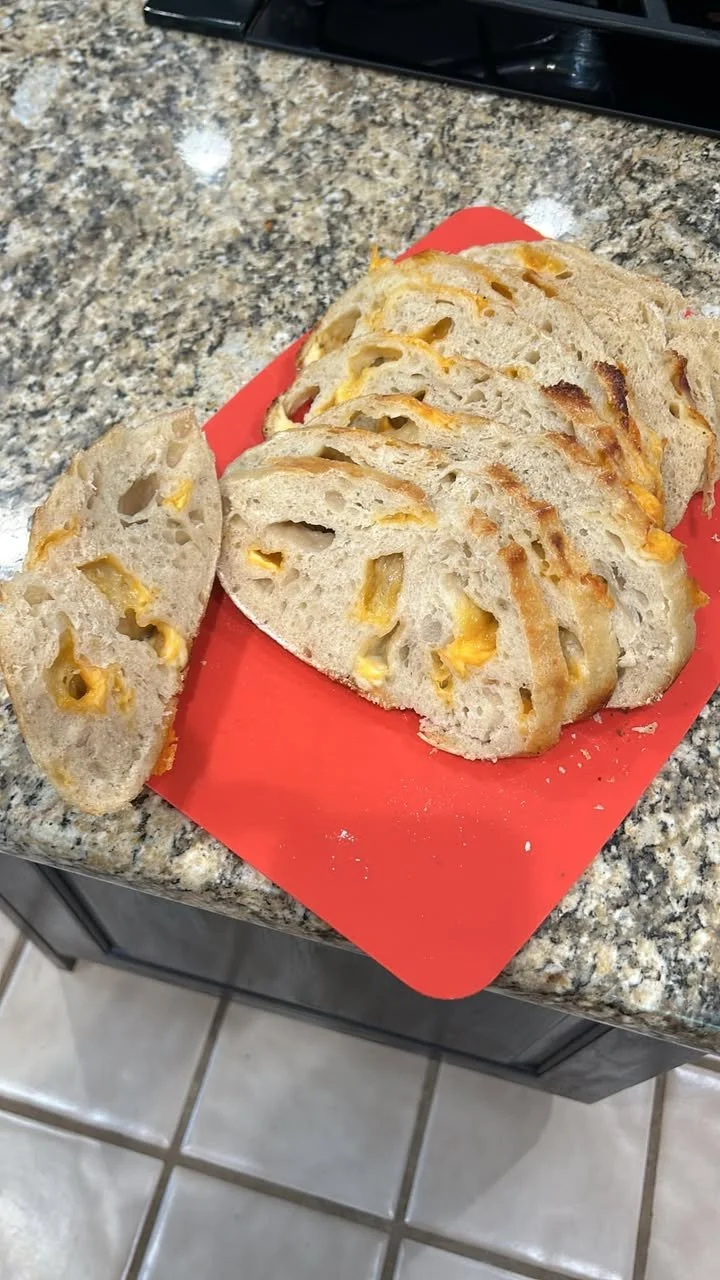 Slices of bread with melted cheese on a red cutting board on a granite countertop.