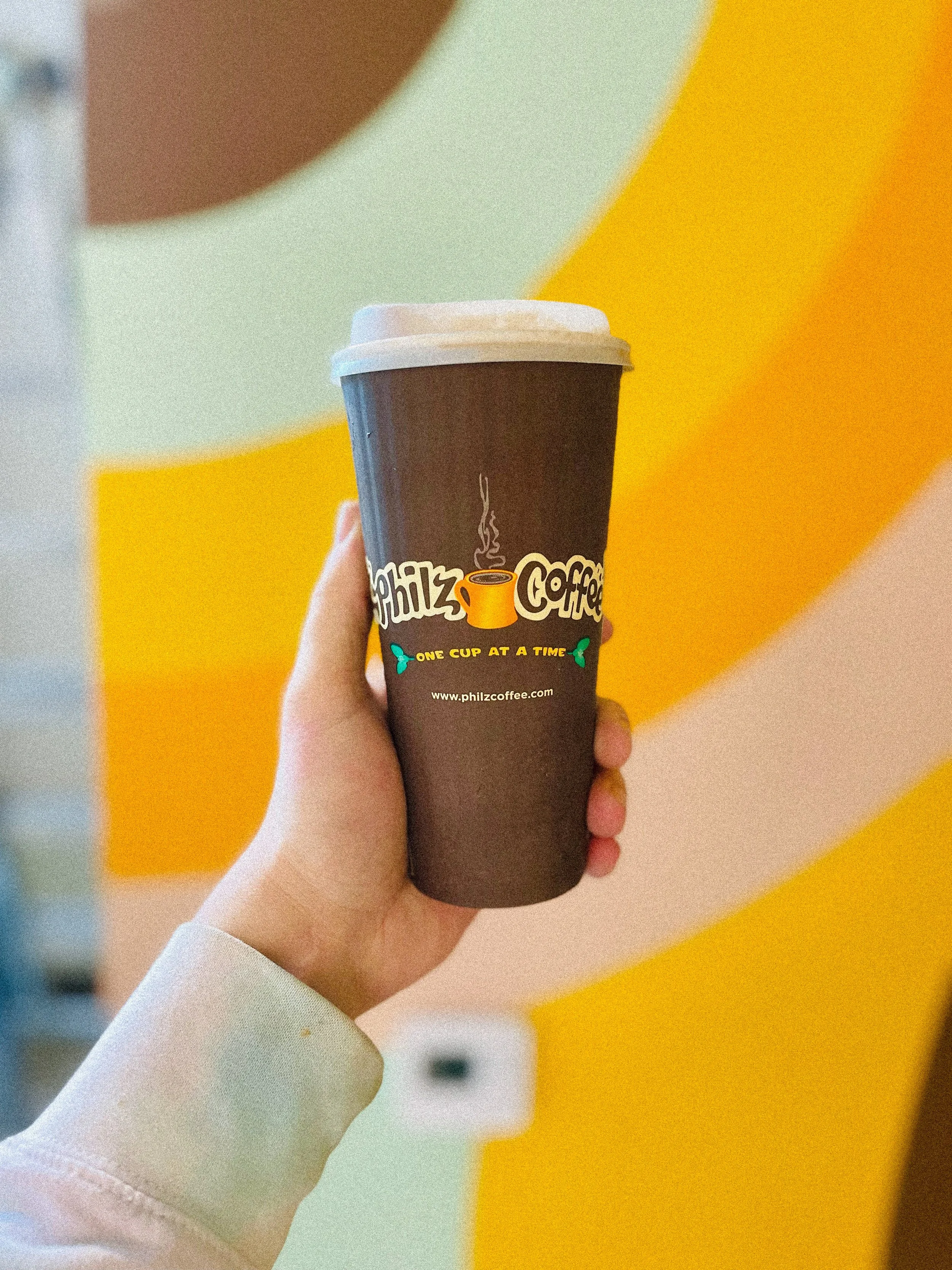 Philz Coffee cup photographed in front of the colorful Calabasas mural