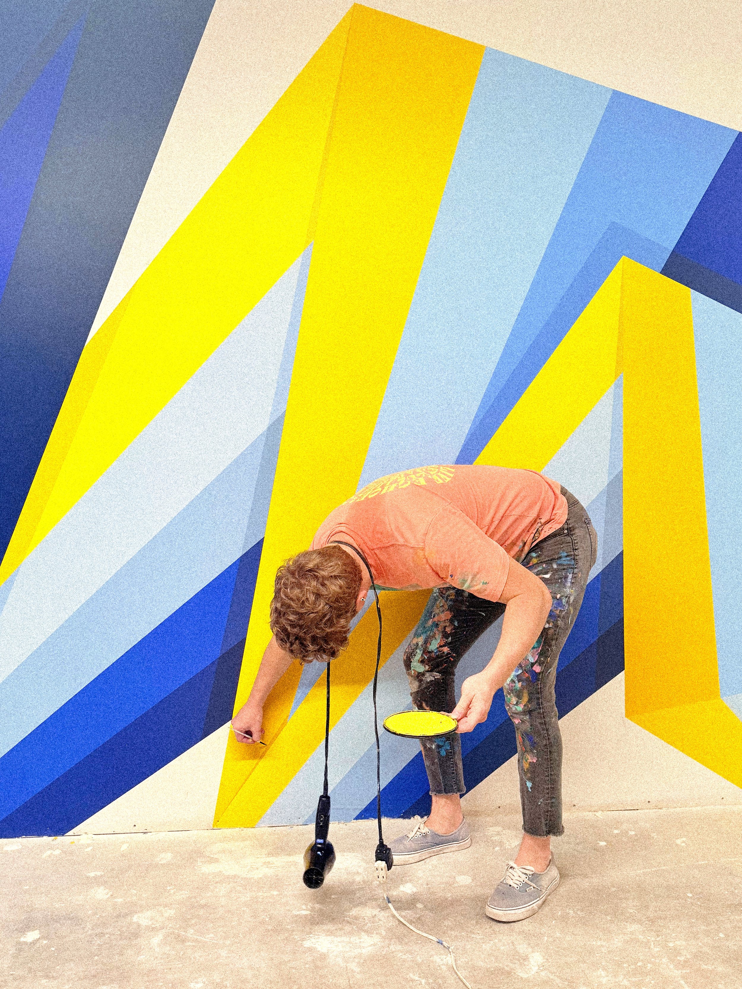Finished geometric mural inside The MARK UCLA fitness center in Westwood, Los Angeles, with bold blue and yellow forms.