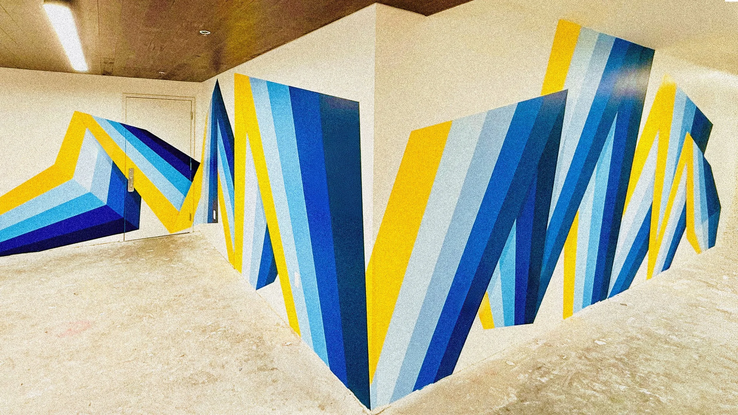 Blue and yellow geometric mural for The MARK at UCLA in Westwood, Los Angeles, featuring layered angular forms.