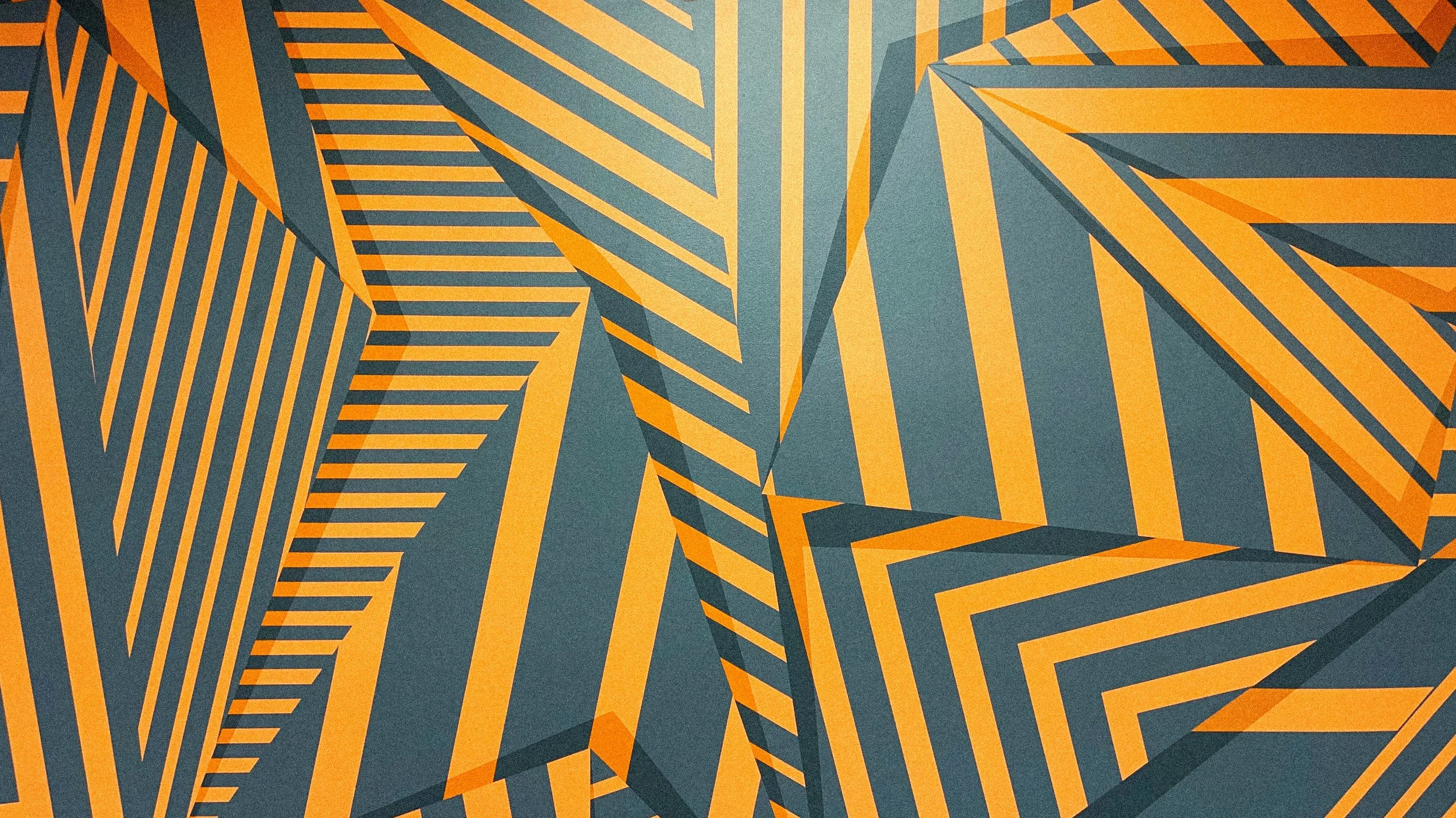 Detail of an orange and charcoal geometric mural showing layered stripes, shifting perspective, and dimensional forms.