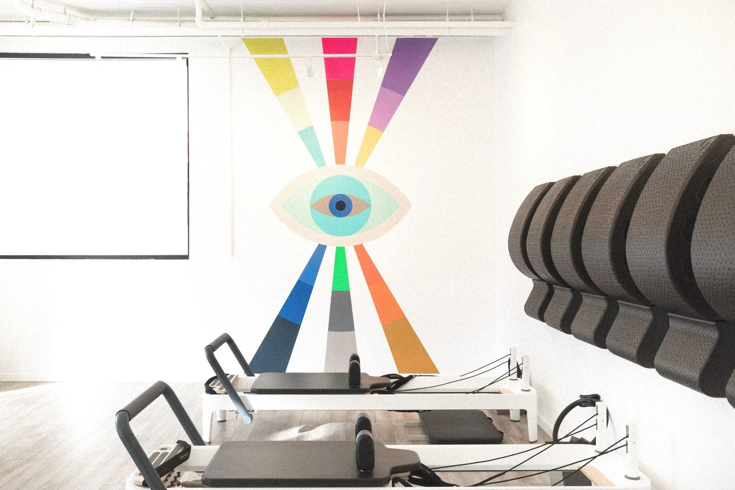 Geometric eye mural with colorful radiating bands inside Samarasa Yoga Studio in Los Angeles.