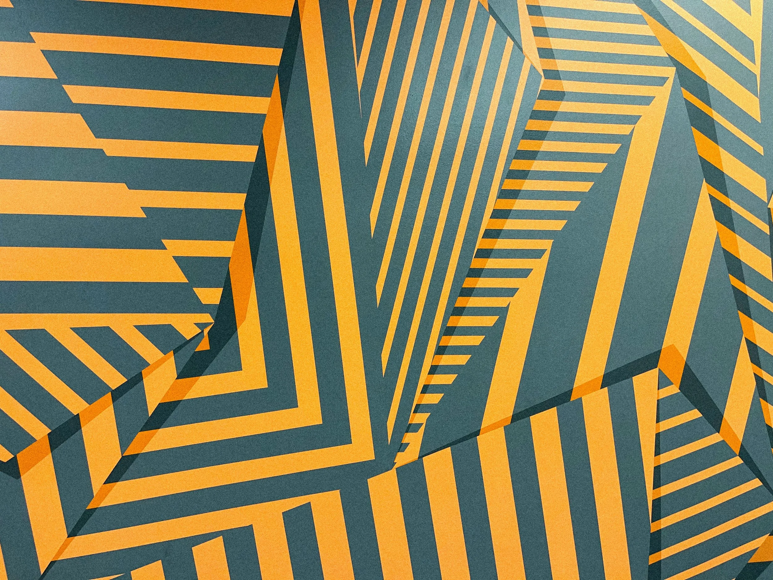 Detail of the Laguna office mural featuring intersecting orange and charcoal stripes arranged into angular three-dimensional forms.