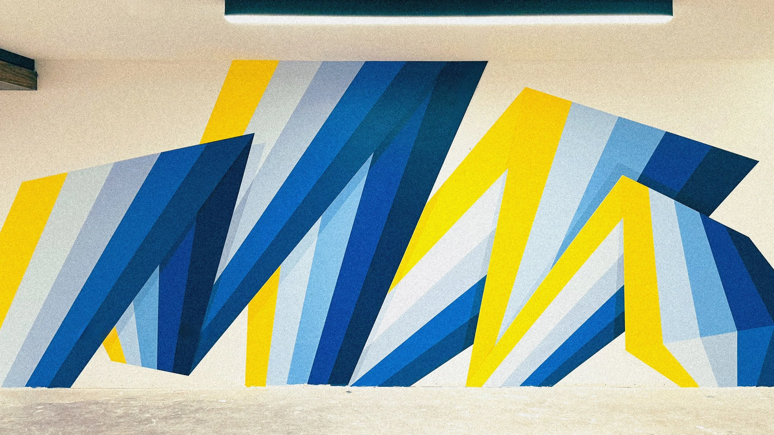 Andrew Haan painting the blue and yellow geometric mural for The MARK at UCLA in Westwood.