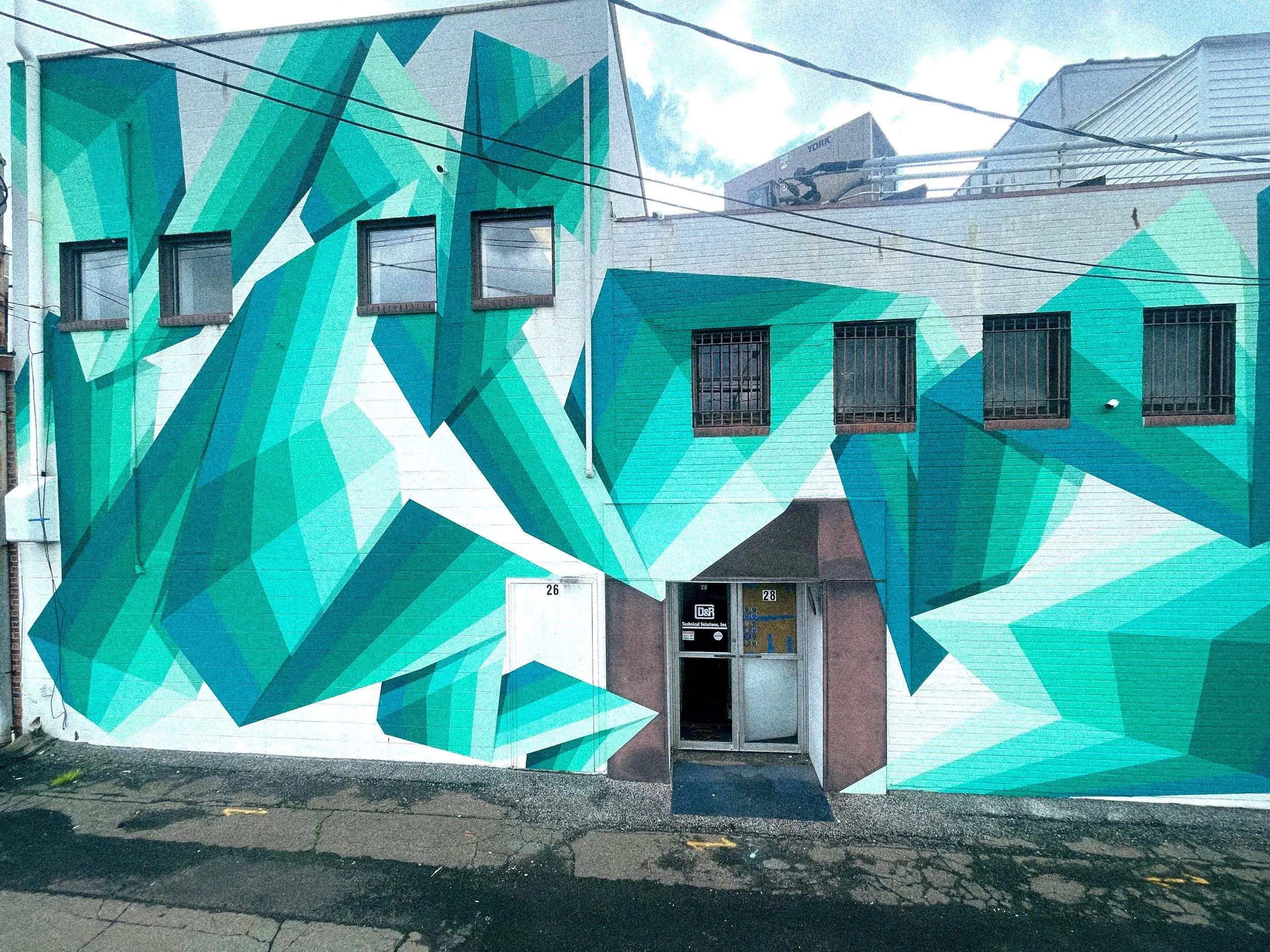 Finished Broome County Arts Council mural with geometric teal forms surrounding the building entrance