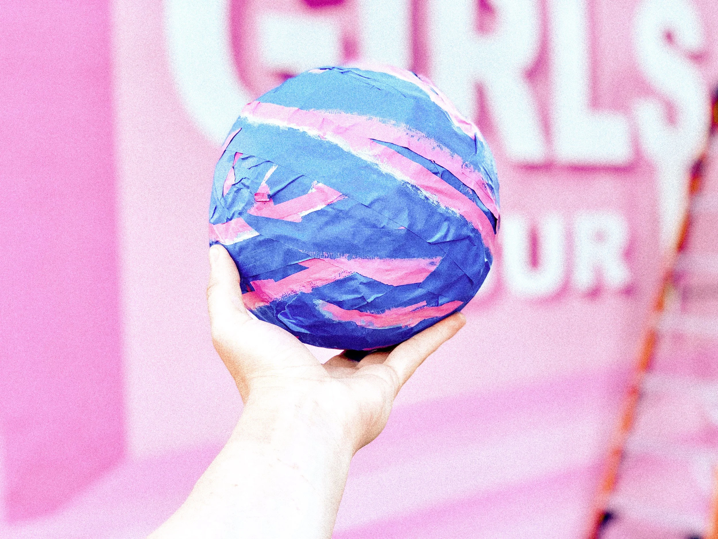 Hand holding a paint-covered ball during the installation of the pink Girls Tour mural in West Hollywood.