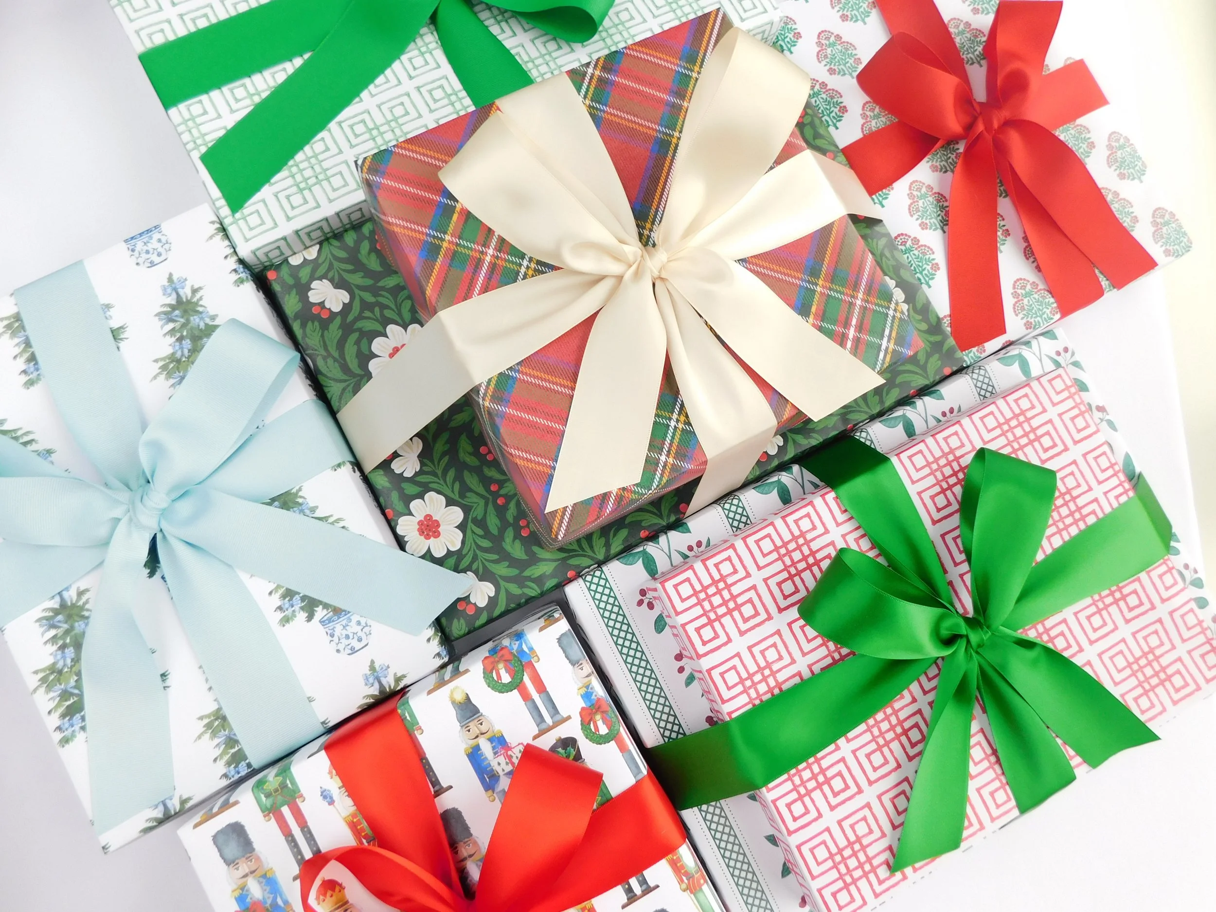 Multiple Christmas wrapped presents with festive bows and ribbons, featuring patterns of holiday icons, including nutcrackers, evergreen trees, and santa wreaths.
