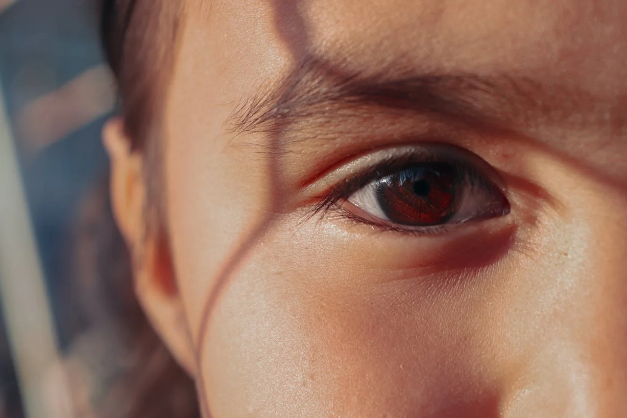 Close-up of a child’s eye and face with sunlight casting shadows across their skin