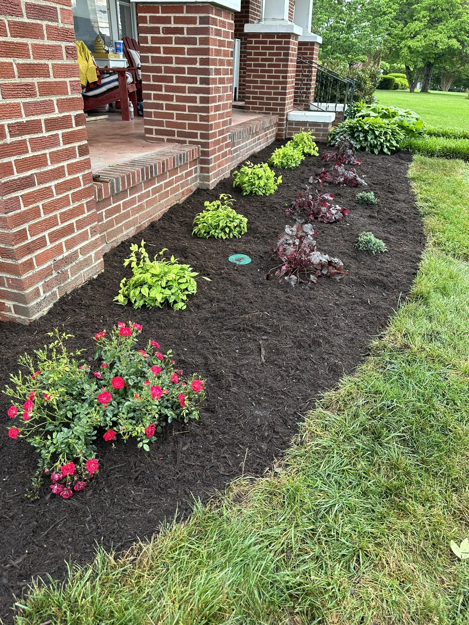 Renovated front landscape bed with fresh mulch, new plants, and enhanced curb appeal.