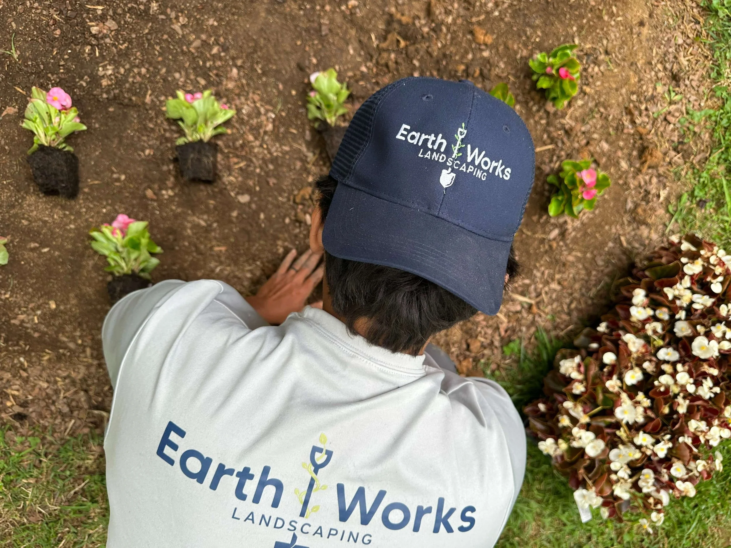 EarthWorks Landscaping team member installing seasonal flowers in a residential landscape bed as part of a custom landscape design project.