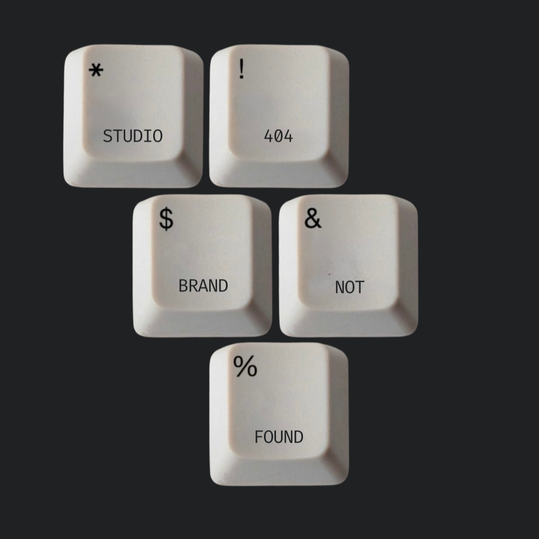 Four white keyboard keys with black text arranged to spell 'STUDIO 404 BRAND & NOT % FOUND' on a black background.