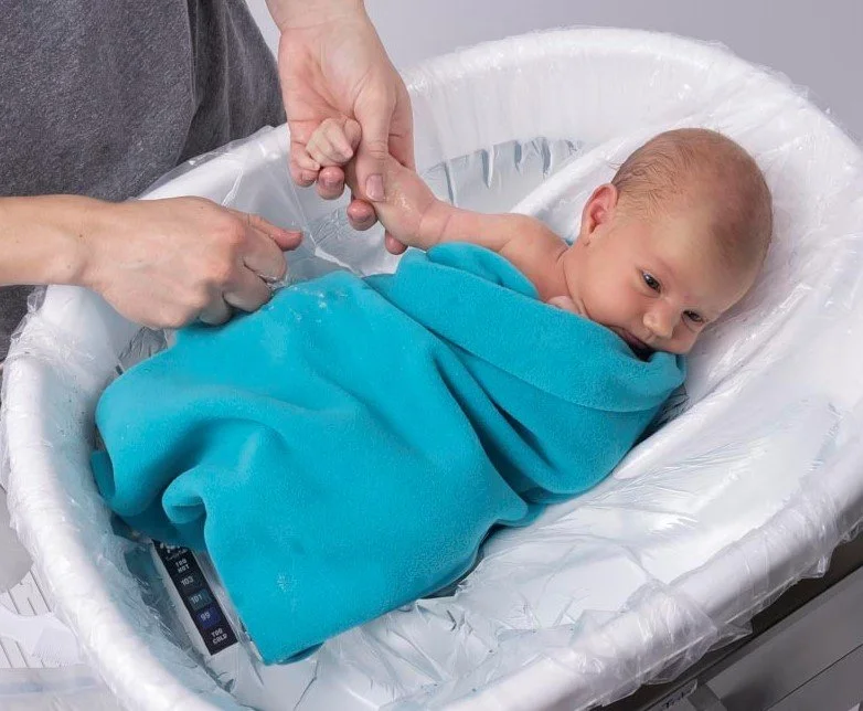Baby in swaddling blanket getting bath in TurtleTub