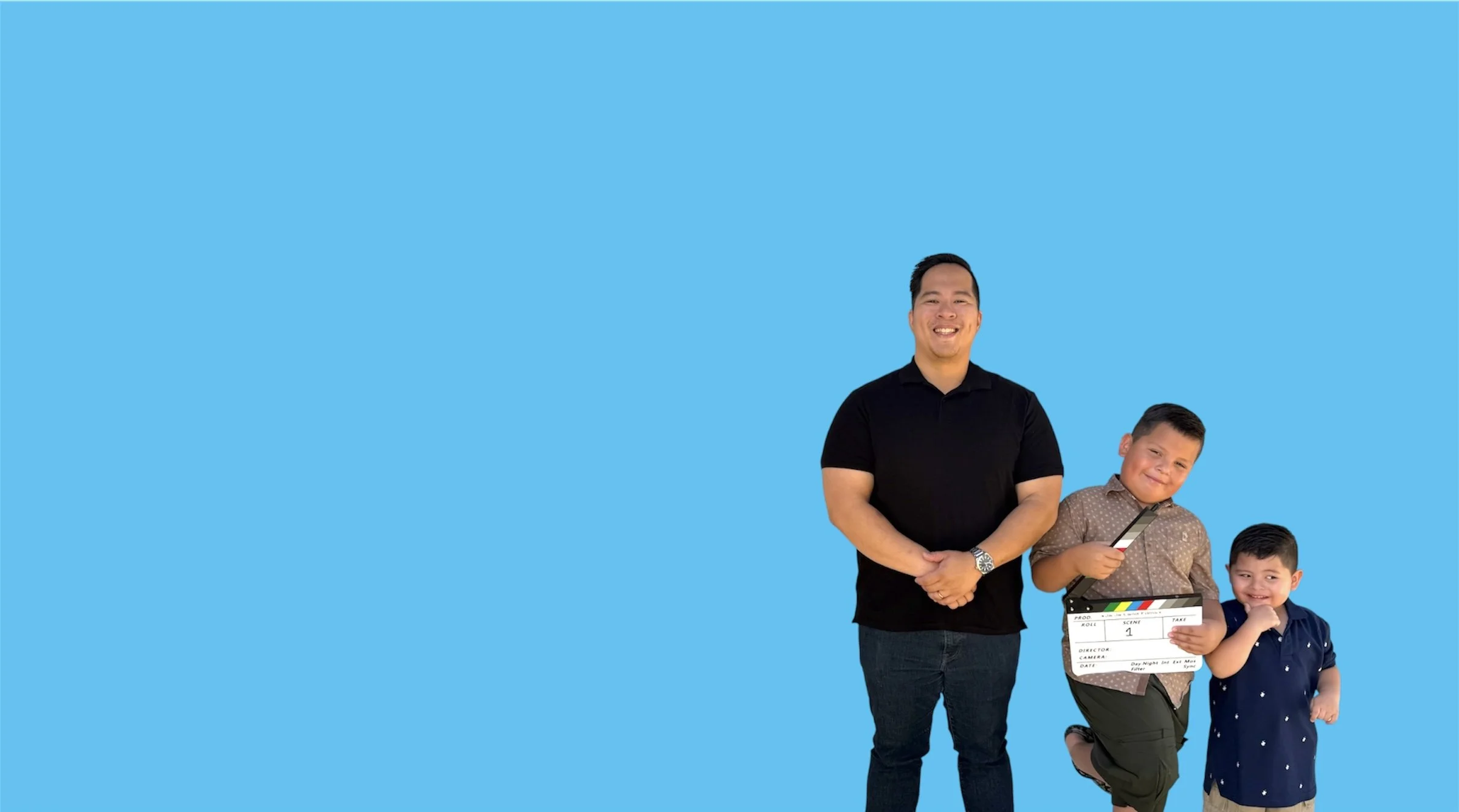 A group of children and an adult standing against a bright blue background, with one child holding a clapboard and a toy knife, and the adult smiling.