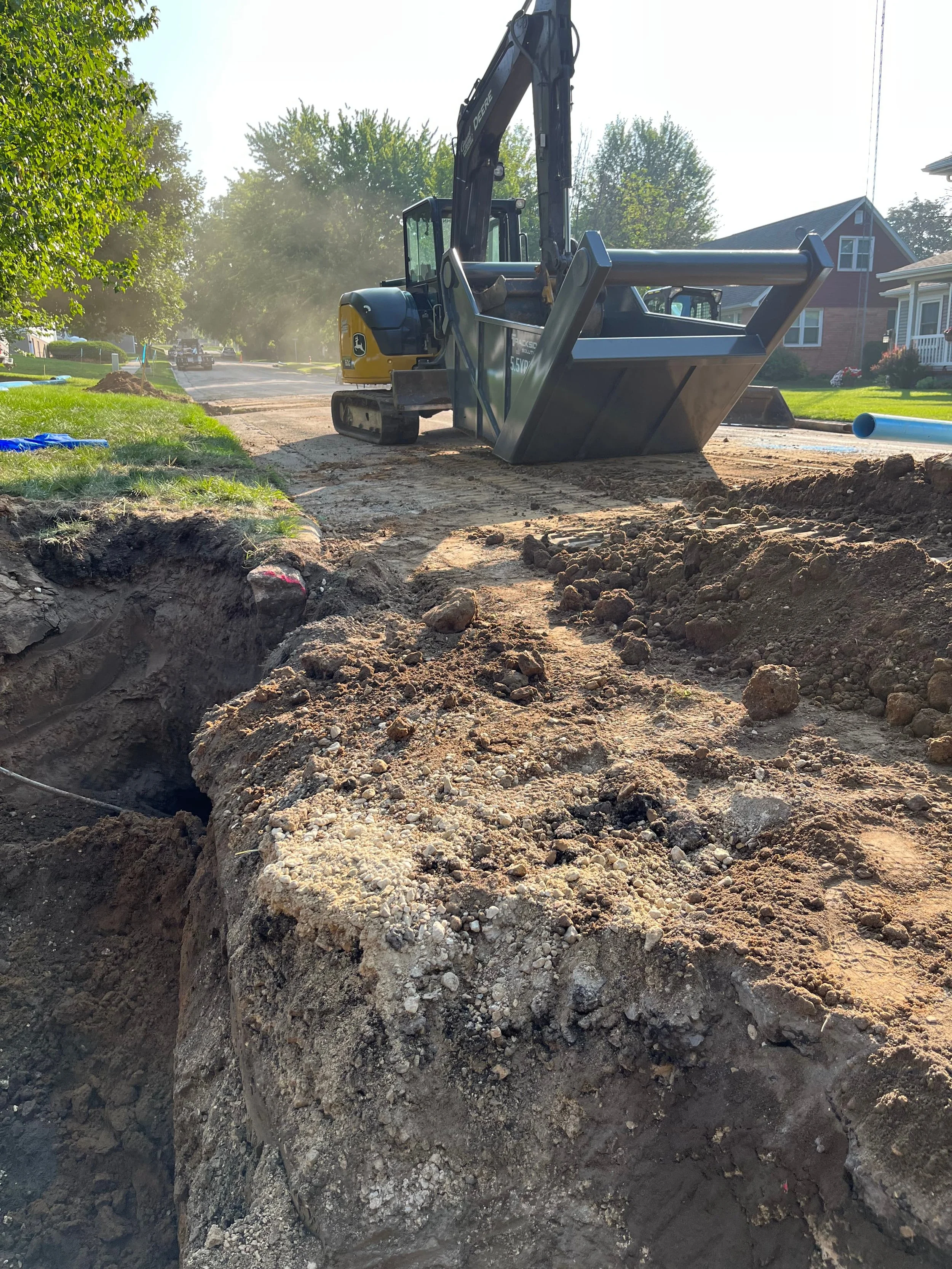 Construction site with an excavator digging a trench on a street.