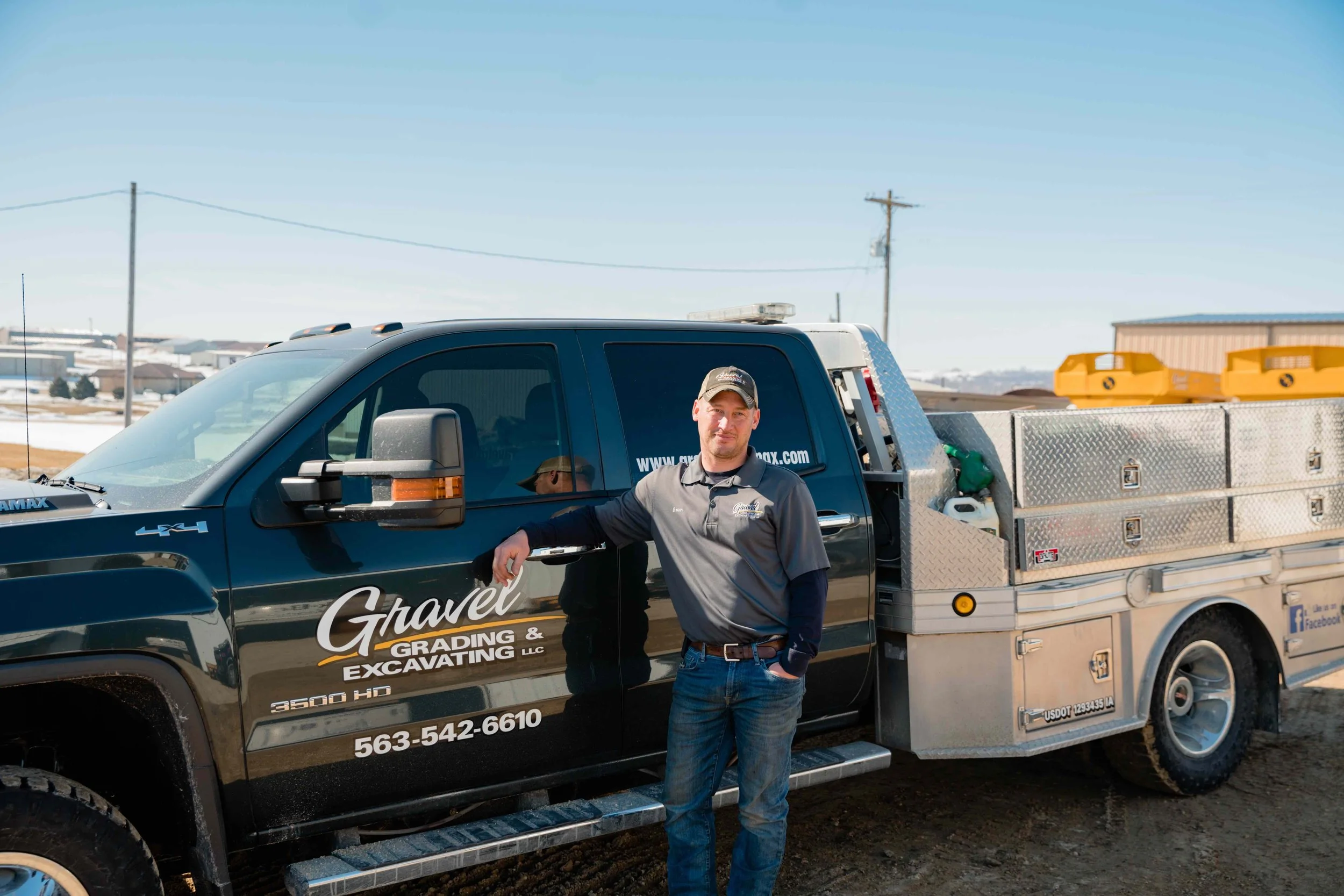 Brian, Gravel Grading & Excavating crew member, standing beside a branded company work truck in Eastern Iowa