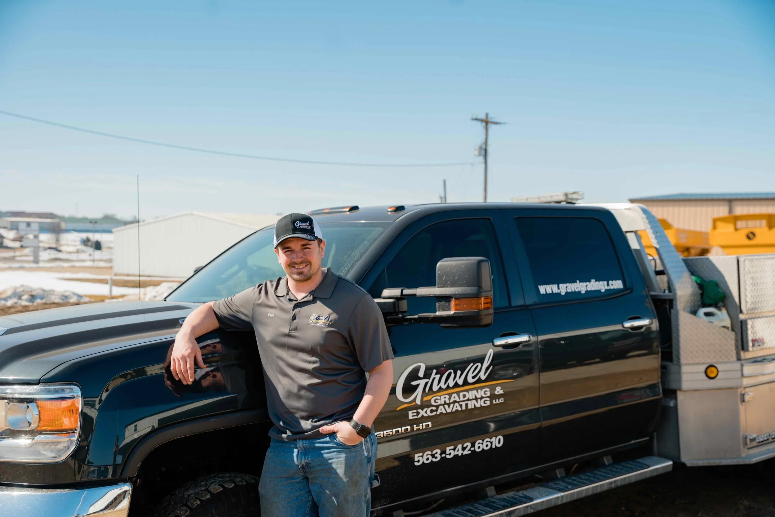 Brad, Gravel Grading & Excavating crew member, leaning against a branded company truck in Eastern Iowa