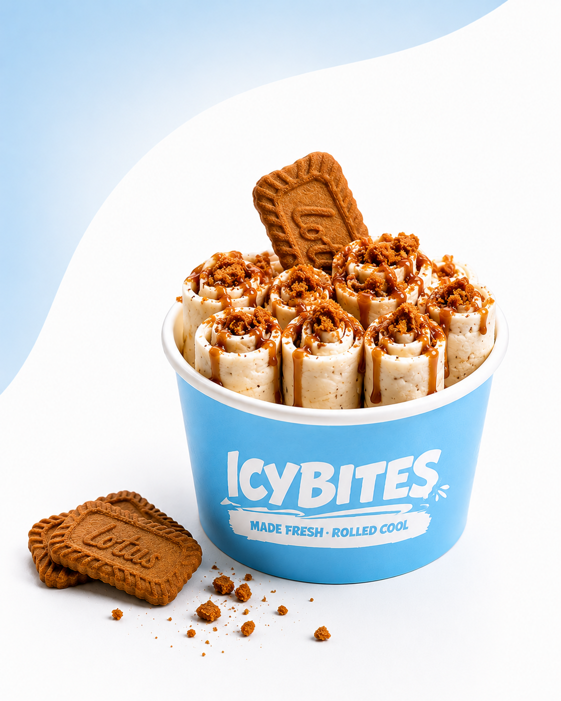 A cup of rolled cookies topped with caramel sauce and crushed cookies, with a Lotus biscuit inserted into the top, all placed against a white and light blue background.
