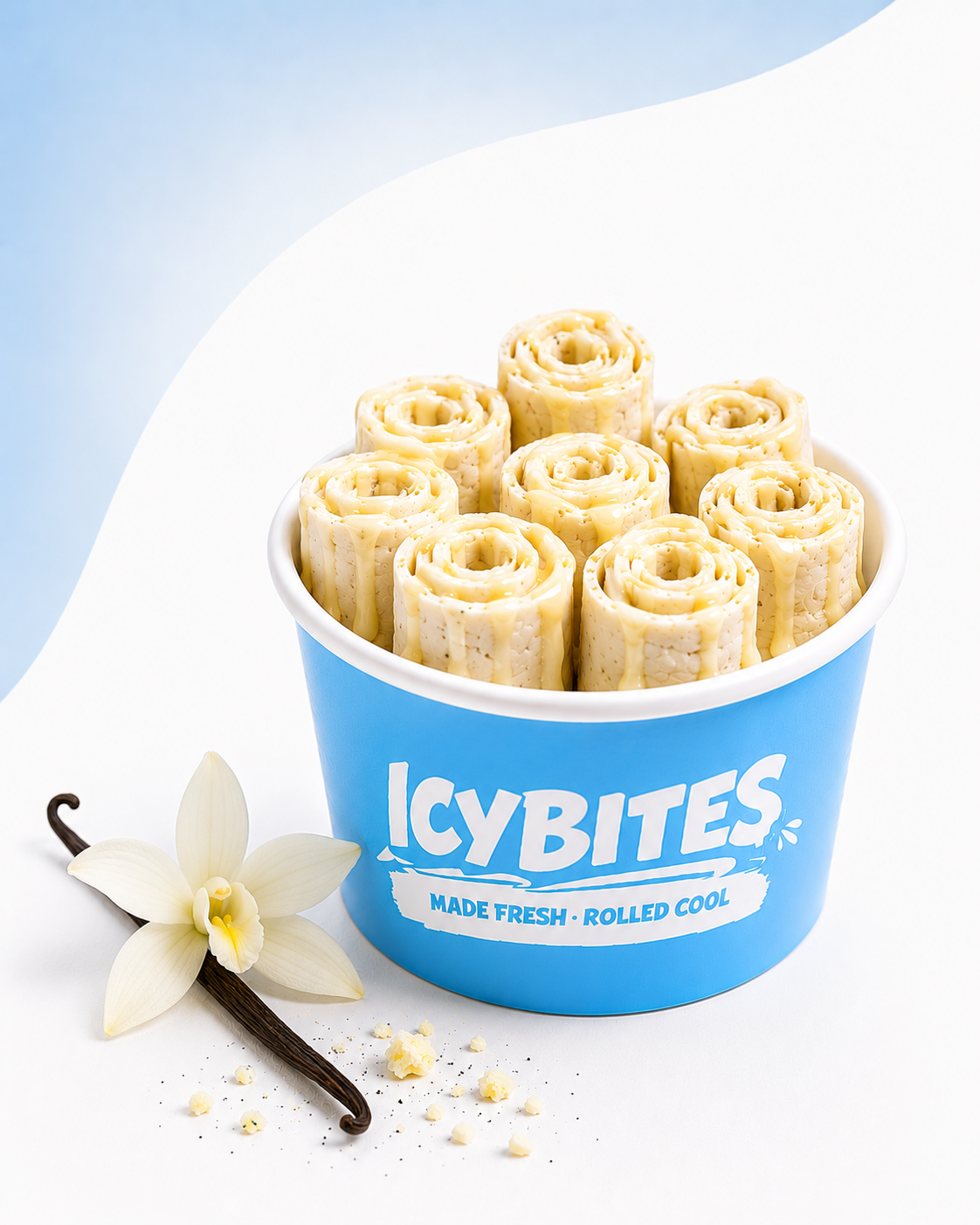A blue cup with the brand name 'ICYBITES' filled with rolled white cheese sticks drizzled with sauce, placed beside a vanilla orchid flower and a vanilla bean, with small crumbles and a vanilla flower on a white surface.