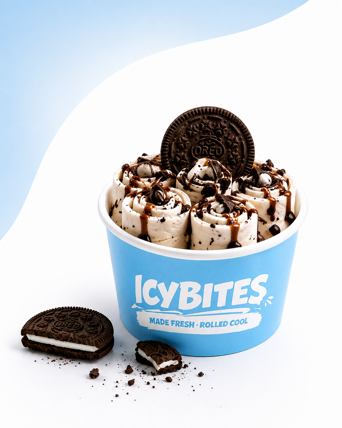 A blue cup labeled "ICY BITES" filled with rolled ice cream topped with chocolate syrup, mini Oreo cookies, and a whole Oreo cookie on top. There are also Oreo cookies and crumbs outside the cup.