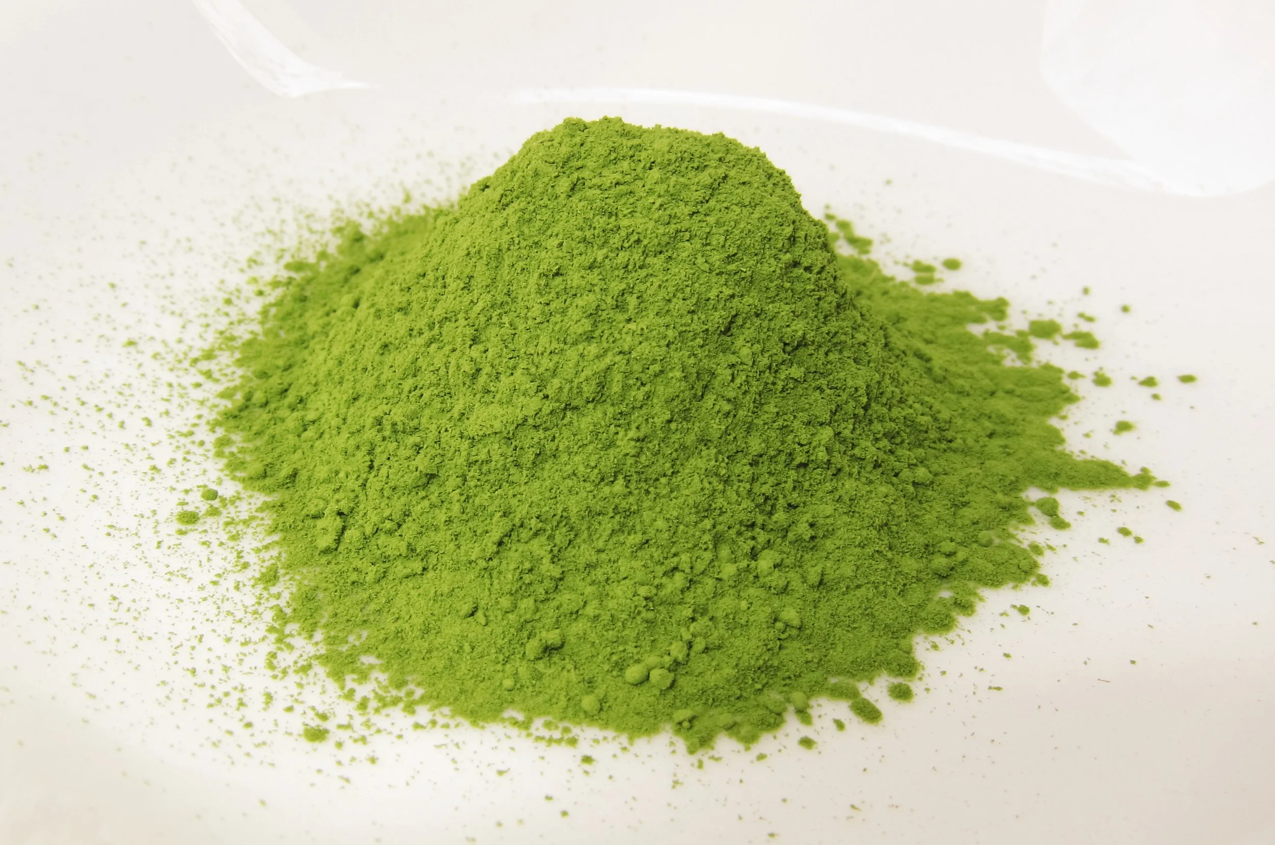 A mound of bright green matcha powder on a white surface.