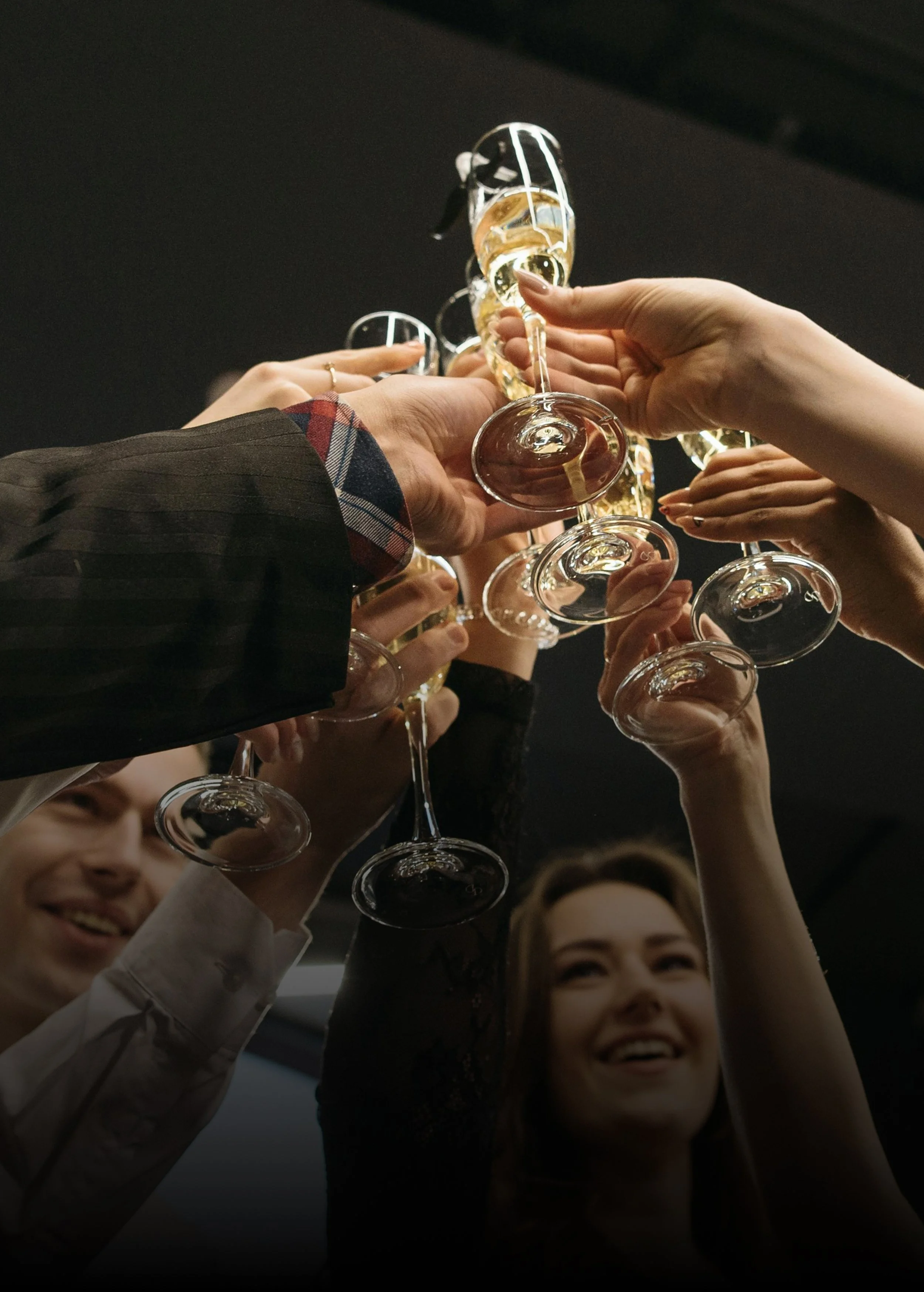Group of people raising champagne glasses in a toast, smiling and celebrating.