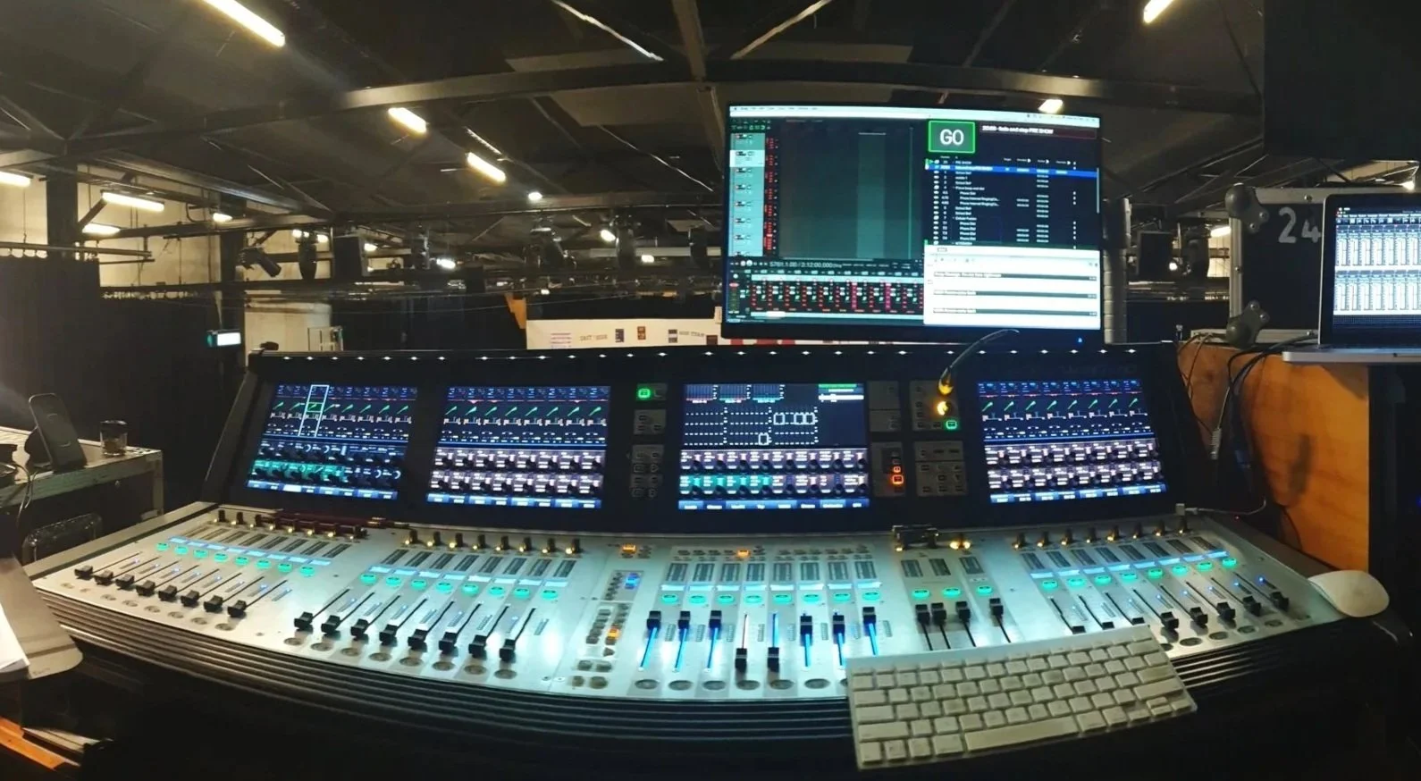 A professional sound engineer's mixing console with multiple screens and controls, in an event space.