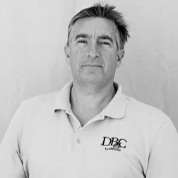 Black and white portrait of a man with short hair, wearing a polo shirt with a logo.