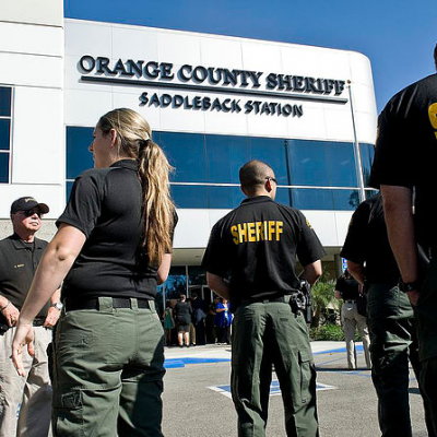 Group of sheriff deputies standing outside the Orange County Sheriff Saddleback Station building.