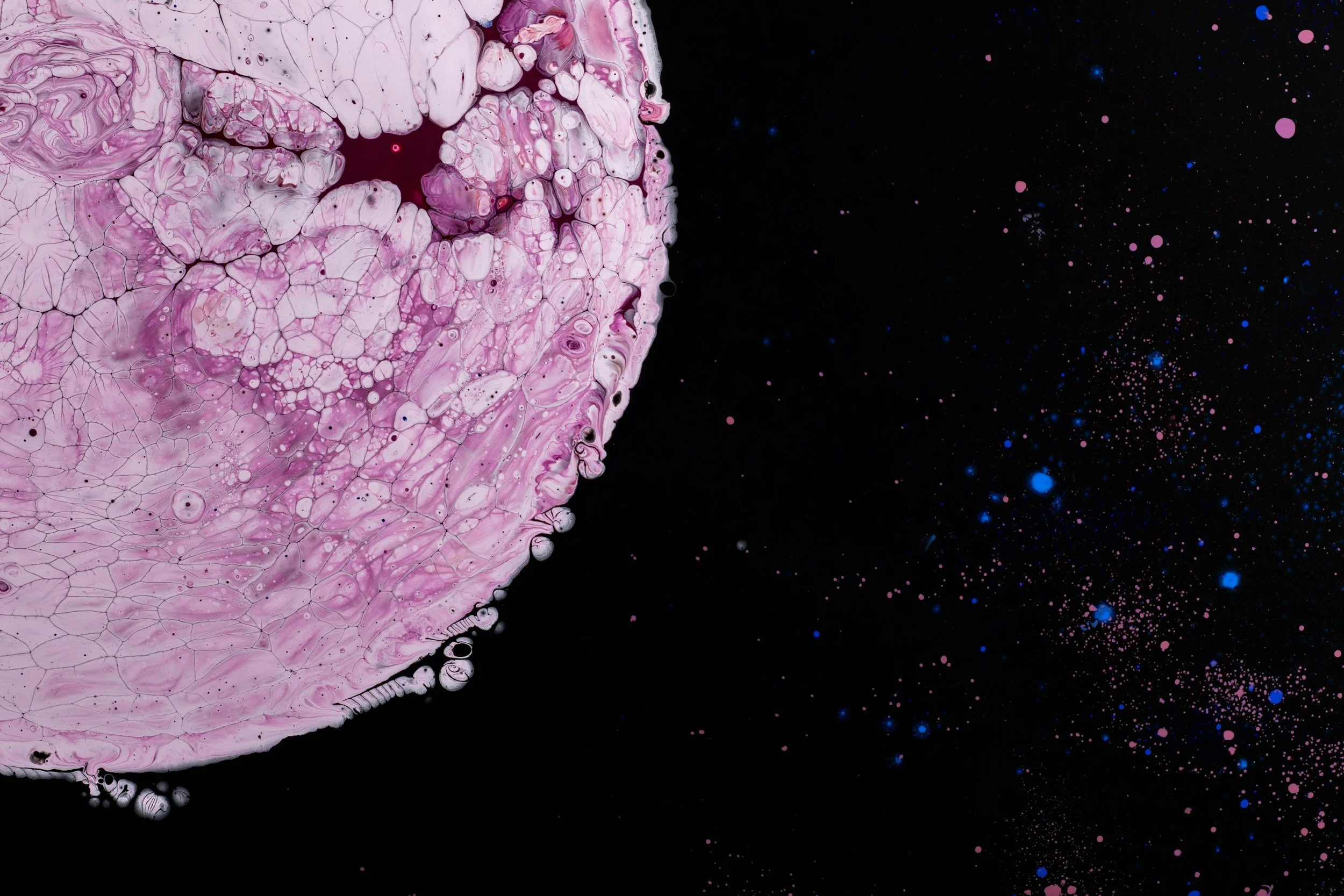 Purple and pink abstract pattern on the left side, resembling a planet or moon, against a black background with scattered pink and blue dots resembling stars.