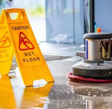 Wet floor caution signs near cleaning equipment in a restaurant.