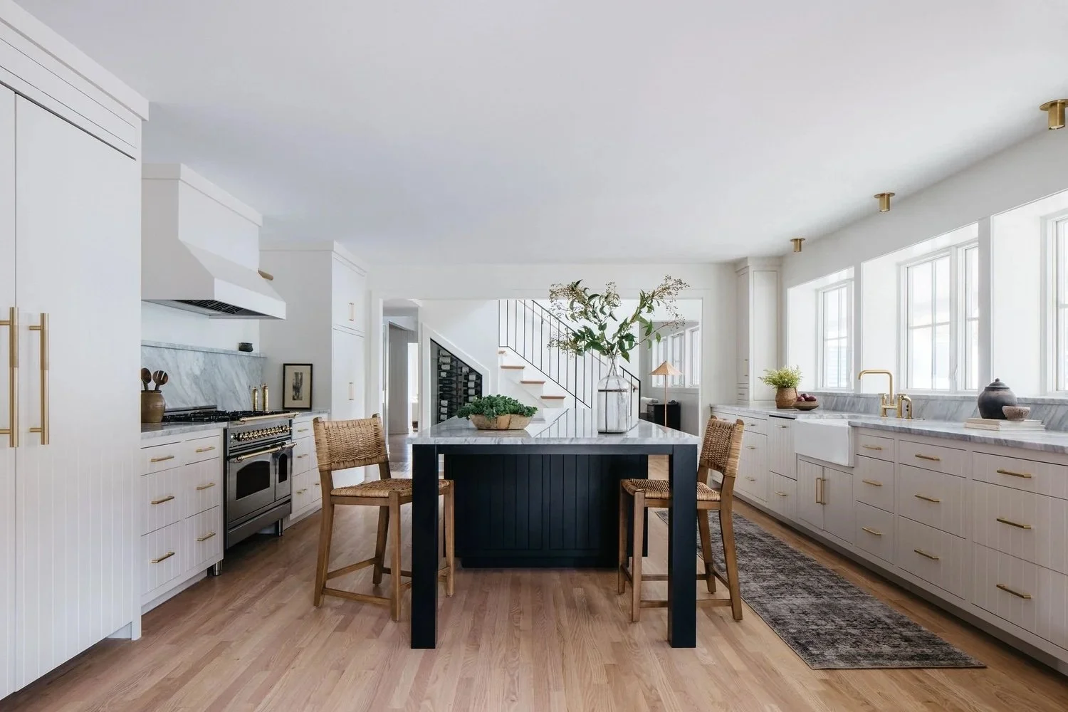 The Hideaway kitchen by a Glen Ellyn interior designer: white cabinetry, black island and woven counter stools