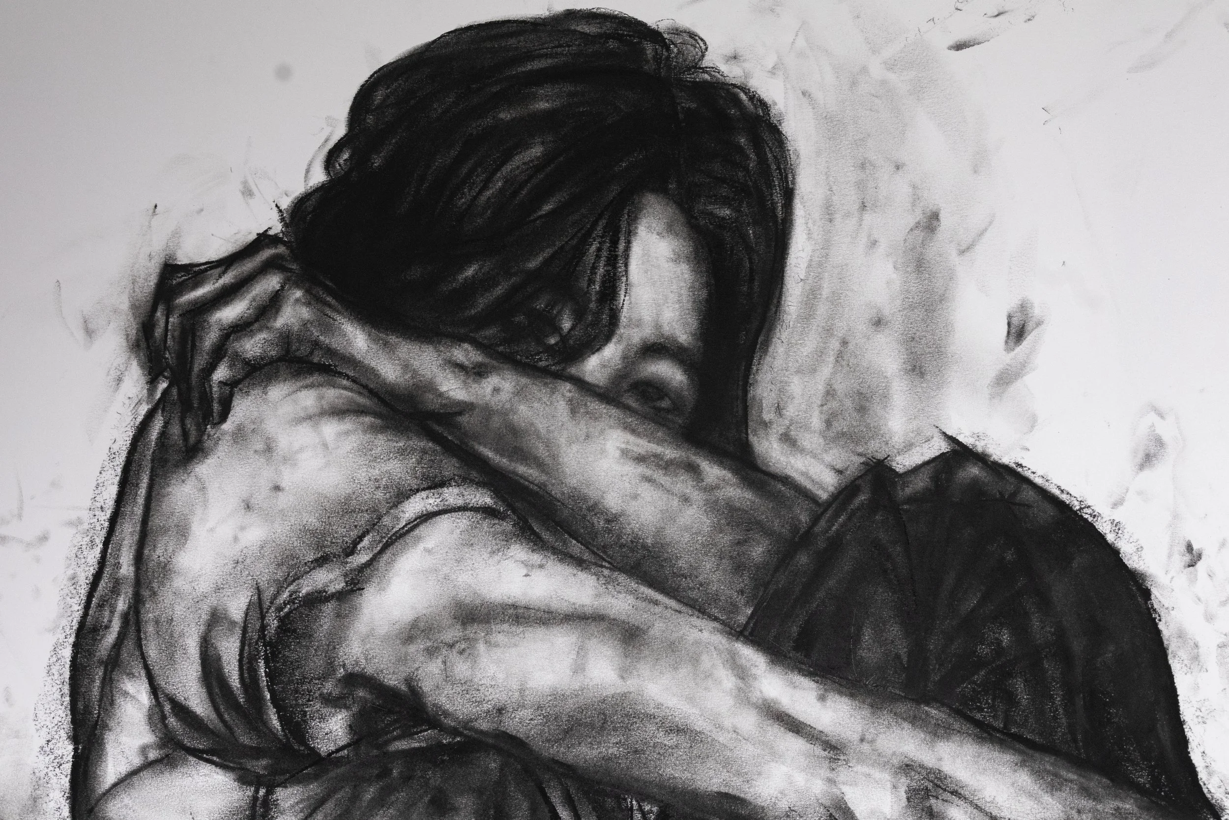 A charcoal or pencil sketch of a woman resting her head on her arms with her hair covering part of her face.