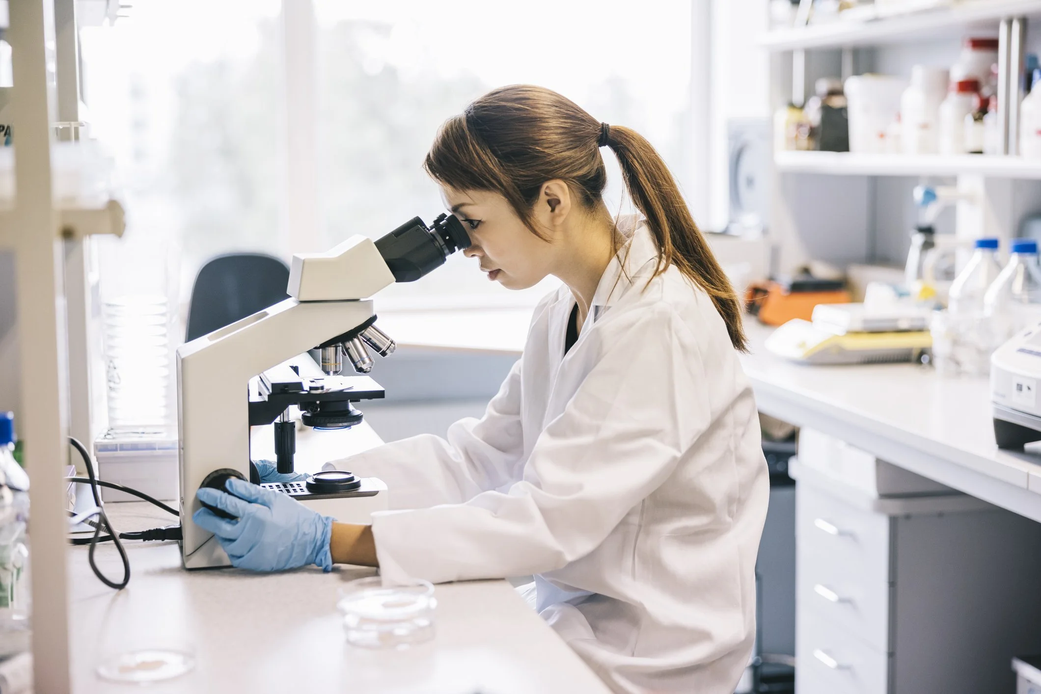 Lab technician working at a station with a microscope.