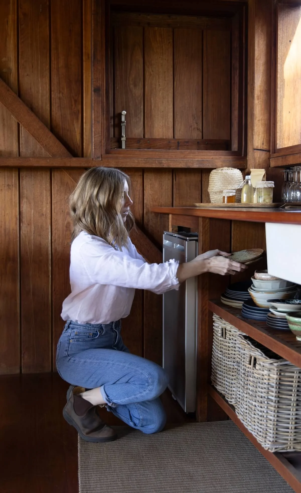 Dr Bea Bobbin offering professional decluttering services in Canberra, organising items on a timber shelf