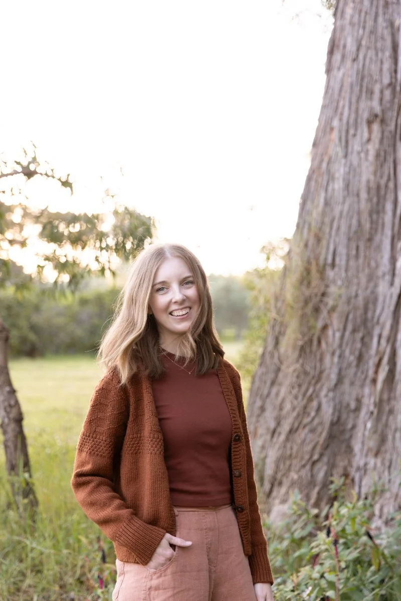 Woman in a rust cardigan smiling outdoors, offering support for anyone searching where to donate in Canberra.