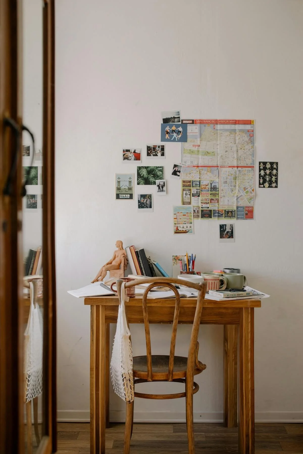 A busy home desk covered in books, papers and pinned maps – the kind of everyday clutter that builds up without a simple system to manage it