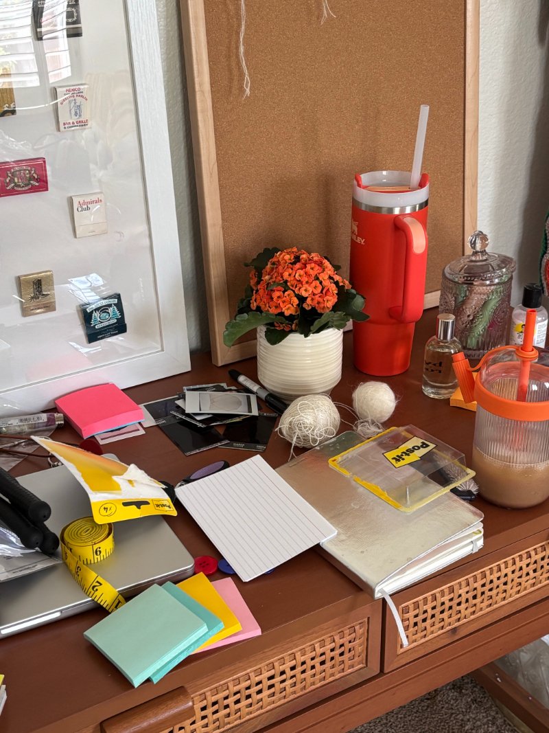 Visual noise on a cluttered desk with sticky notes, index cards, string, a tape measure and drinks