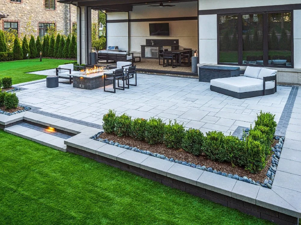 Modern backyard patio with fire pit, outdoor furniture, built-in outdoor kitchen, and landscaped garden