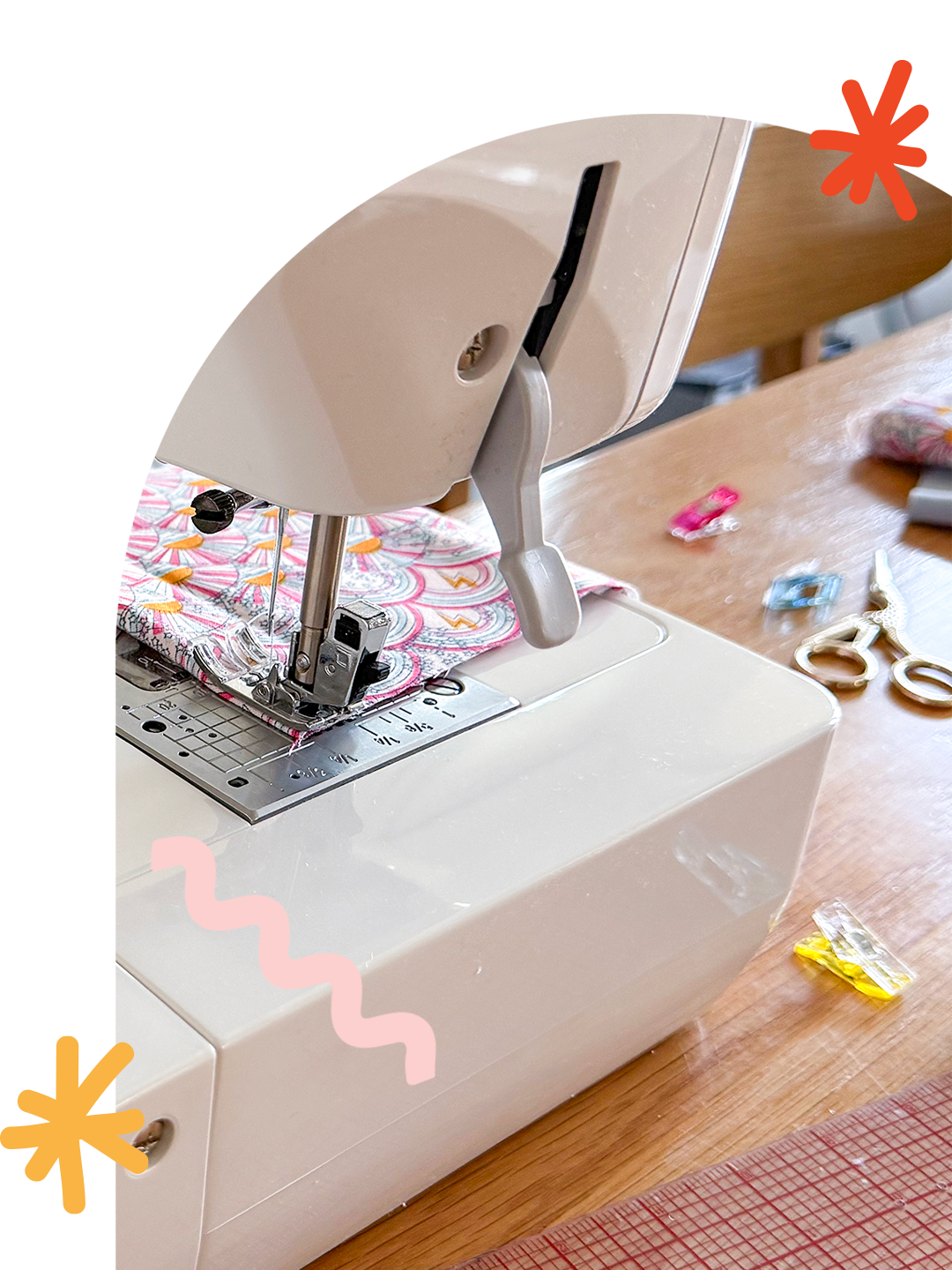 Sewing classes and workshops in Jersey City. Close-up of a sewing machine stitching a folded fabric with pink, orange, and white patterns, placed on a wooden table surrounded by scissors, clips, and a ruler.
