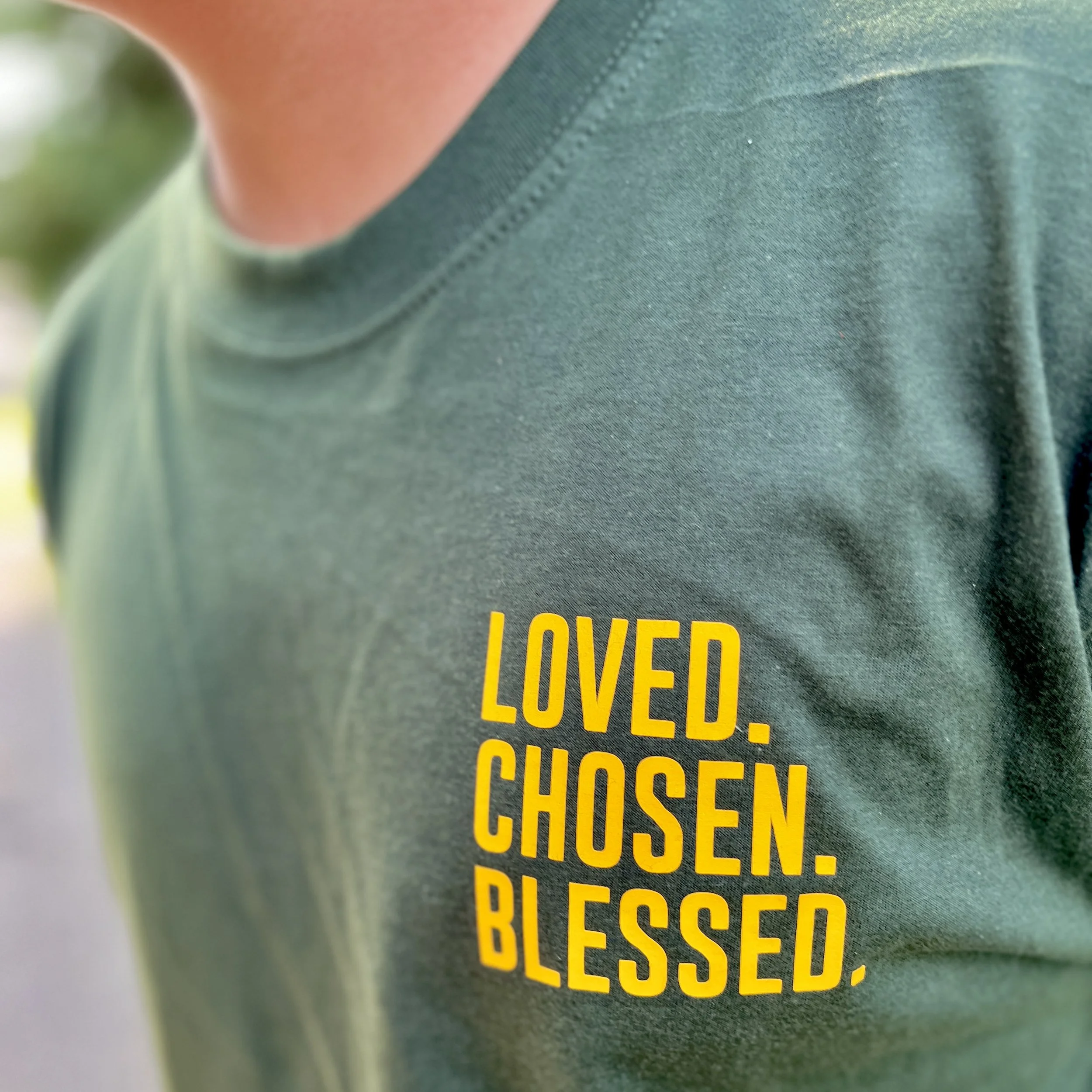 Close-up of a green book cover with yellow text that reads 'LOVED. BLESSED. CHOSEN.'