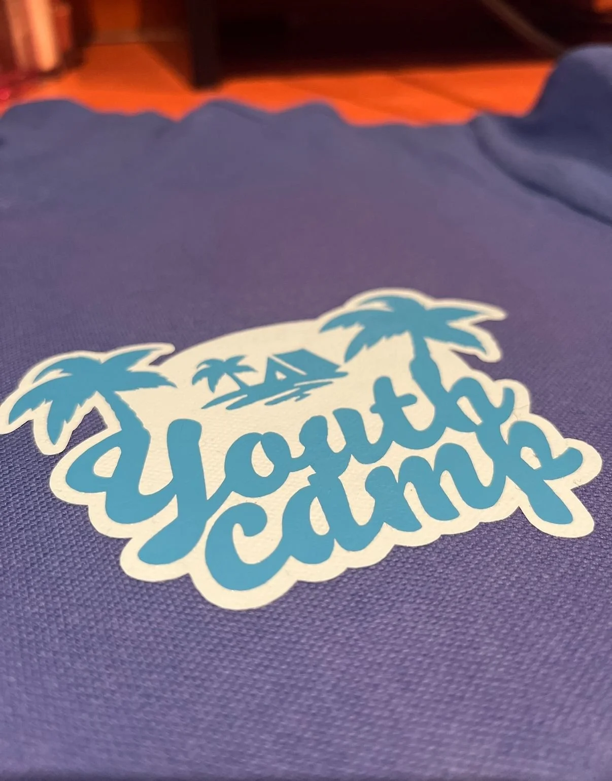 A sticker on purple fabric featuring the words 'South Beach' with palm trees and a small building, suggesting a beach or tropical location.