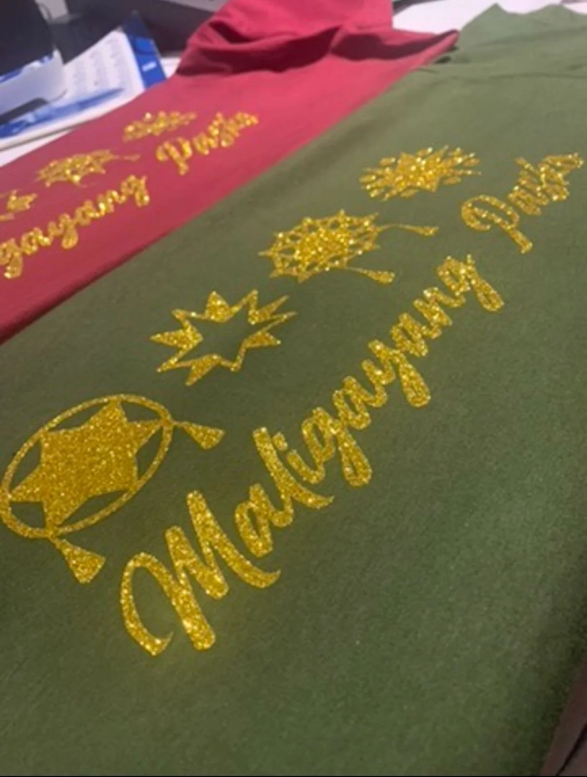 Gold glittery holiday decorations with Christmas tree, stars, and decorative text on a green background.