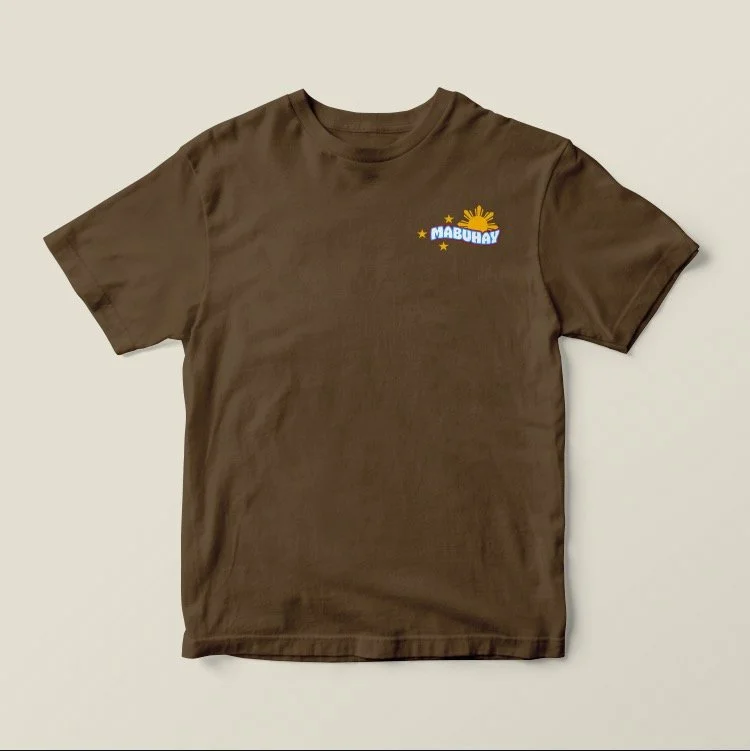 Brown T-shirt with a colorful graphic that says "MABUHAY" and includes a sun, stars, and a rainbow.