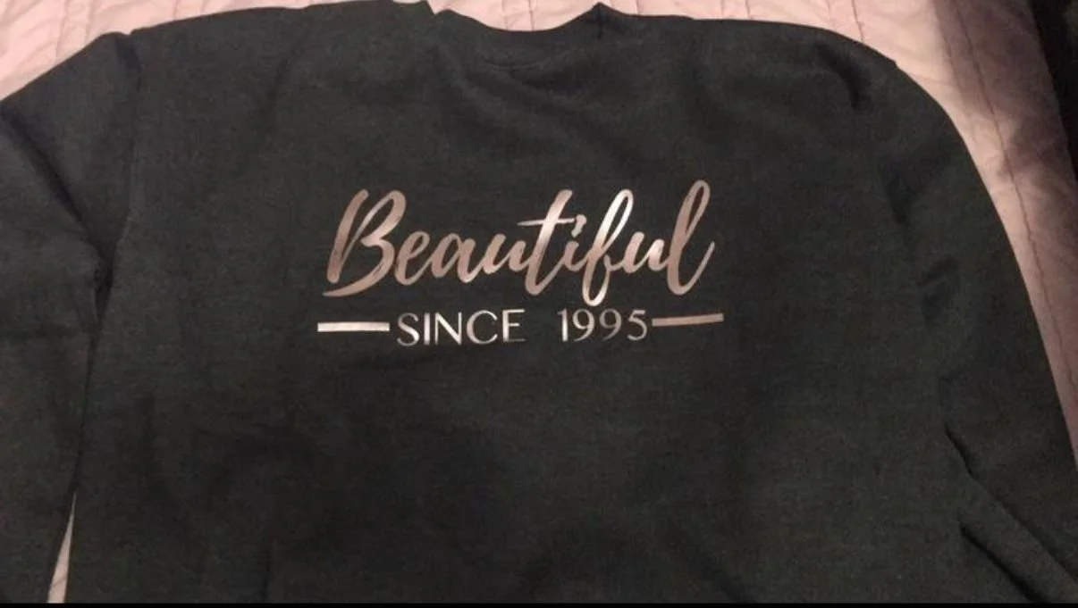 Back of a black shirt with the words "Beautiful Since 1995" printed on it.