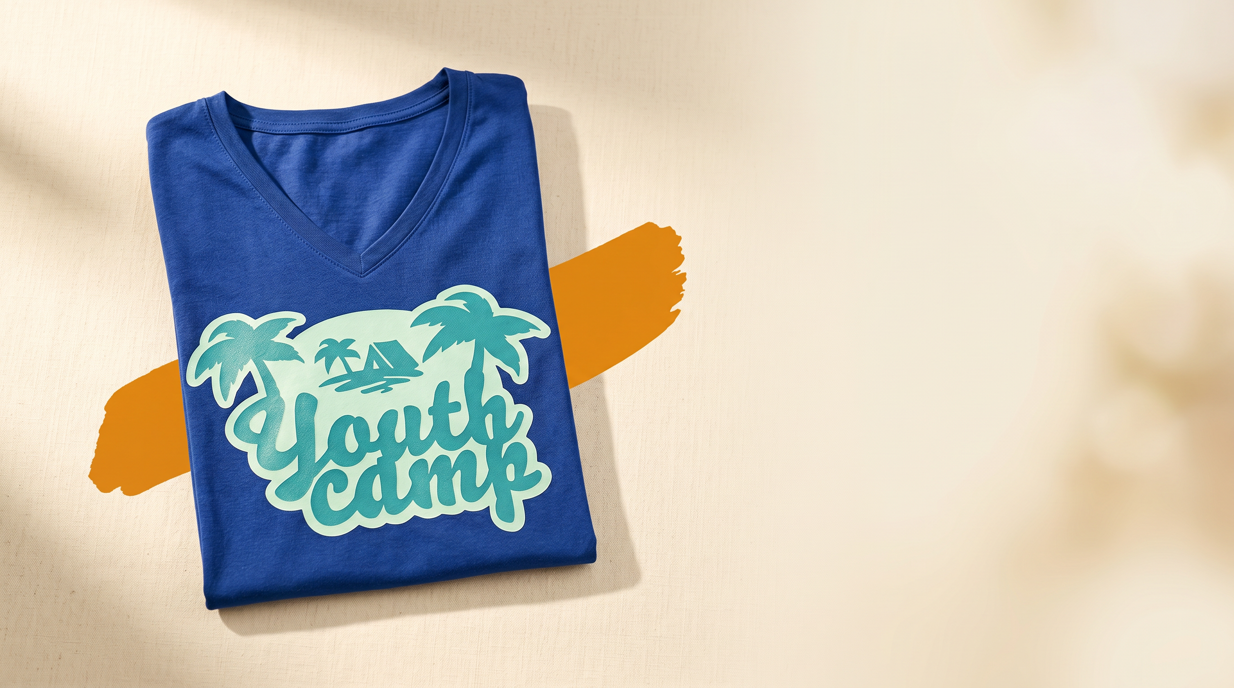 A folded blue T-shirt with a graphic design featuring palm trees and the words "Youth Camp" on a beige surface with an orange brushstroke behind it.