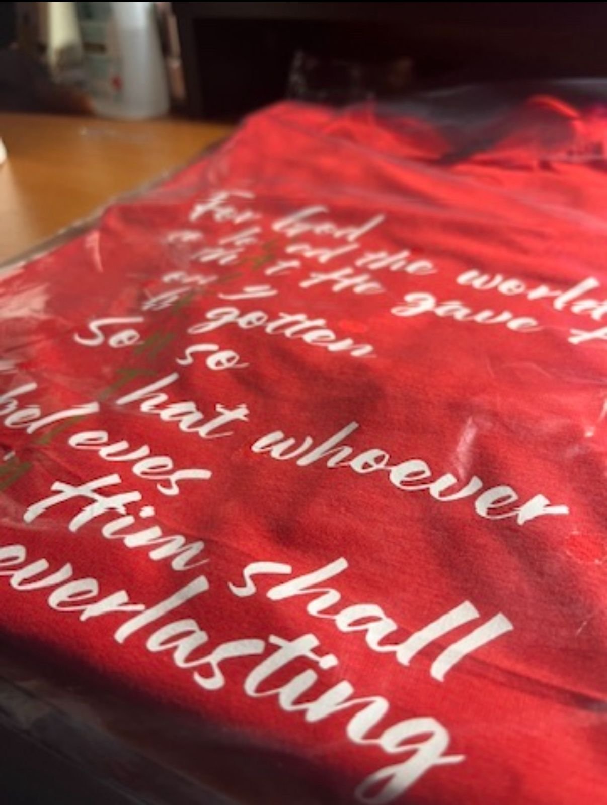 Close-up of red fabric with white cursive writing that appears to be a quote or message, partially obscured.